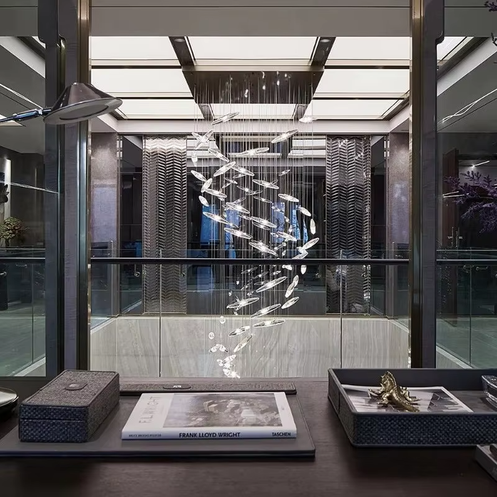 This is a modern artistic fish school-shaped hanging chandelier, featuring multiple silver fish-shaped decorations (crystal/metal texture) suspended by thin wires. The design is dynamic, modern and full of artistic tension, with brilliant and exquisite lighting. It is used for space lighting and artistic decoration, creating a high-end modern artistic atmosphere. Suitable for high-ceiling areas of high-end hotels, luxury commercial clubs, modern art villas and other places.