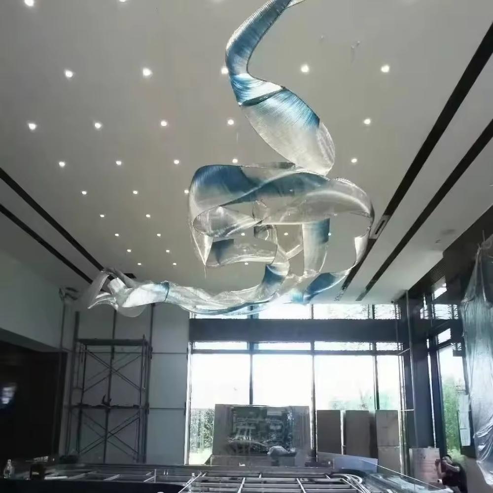 This is an artistic streamline chandelier with a flowing ribbon shape in blue and white gradient, featuring great dynamism and artistry. It is used for space lighting and artistic decoration, significantly enhancing the artistic atmosphere and visual impact of the space. It is suitable for high-end hotel lobbies, art galleries, atriums of large commercial spaces and other places.