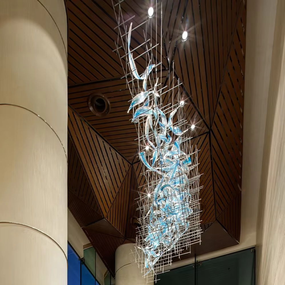 This is a modern artistic metal grid blue transparent decorative chandelier, with a metal grid as the frame, paired with flowing blue transparent shape decorations, and lights dotted in it, creating a dynamic artistic space atmosphere.