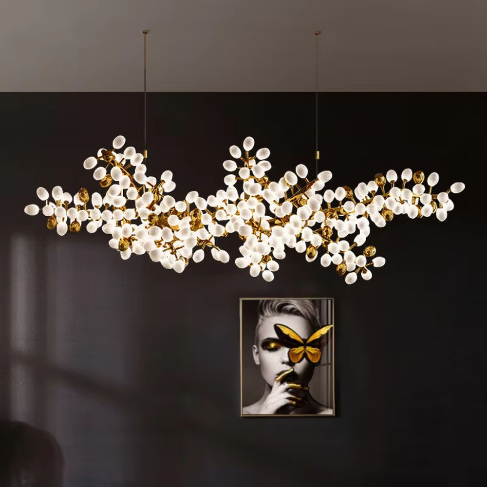 This is a light luxury artistic long strip flower branch-shaped chandelier, with golden metal branches paired with a large number of white spherical lampshades. The shape is like blooming flower branches, with soft and brilliant lighting, creating a light luxury artistic atmosphere.