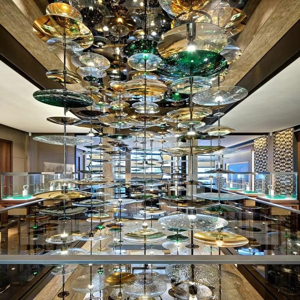 This is an artistic multi-layer glass disc chandelier, composed of multi-colored glass discs (gold, green, transparent, etc.) hung in multiple layers, featuring a strong artistic sense and visual hierarchy. It is used for space lighting and artistic decoration, creating a luxurious artistic atmosphere. It is suitable for high-end commercial exhibition halls, art spaces, luxury hotel lobbies and other places.