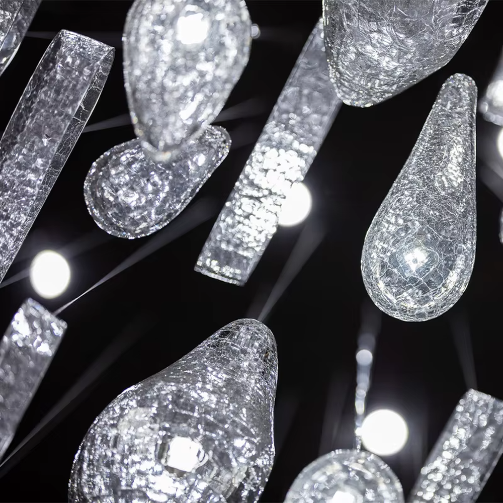 This is an artistic installation-style irregular transparent glass hanging chandelier, composed of numerous irregular transparent glass elements (spherical, block-shaped, etc.) hanging in a scattered manner by thin wires to form a three-dimensional layer. It features soft light refraction and a strong sense of modern art and spatial tension. It is used for space lighting and artistic decoration, creating a modern artistic and ethereal atmosphere. Suitable for high-end hotel lobbies, art exhibition halls, high-ceiling spaces in luxury villas and other places.