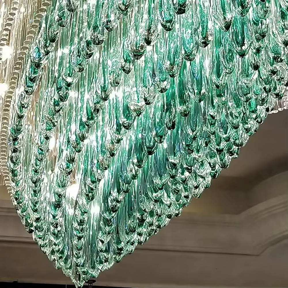 This is an artistic turquoise glass chandelier, with multi-layer turquoise glass components in an irregular hanging shape, transparent and brilliant texture, featuring extremely artistic and luxurious design. It is used for space lighting and decoration, creating a high-end artistic luxury atmosphere. It is suitable for high-end hotel lobbies, luxury banquet halls, art exhibition halls and other places.