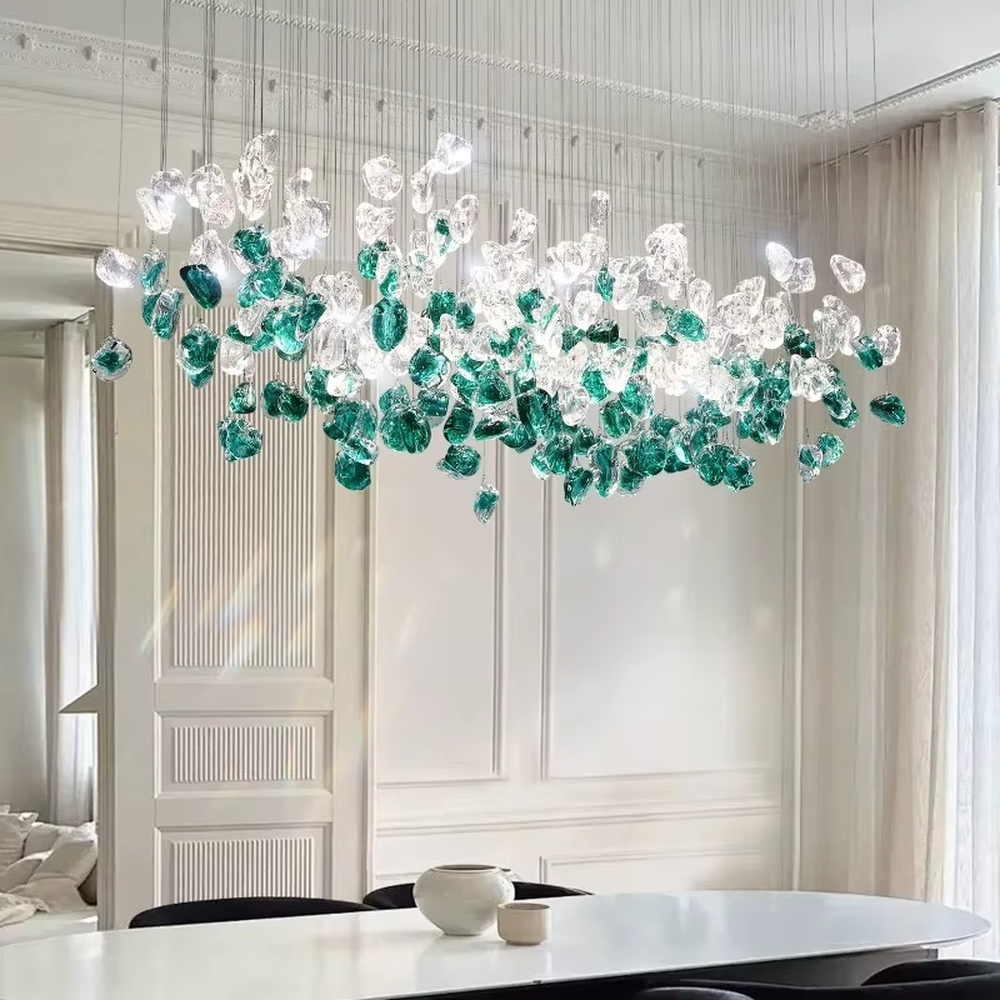 This is an artistic glass stone chandelier, with blue-green and transparent glass stones distributed irregularly in a hanging structure, featuring a modern artistic design with strong luxury artistic sense. It is used for space lighting and decoration, creating an artistic luxury atmosphere. It is suitable for modern luxury home living rooms, art exhibition halls, high-end restaurants and other places.