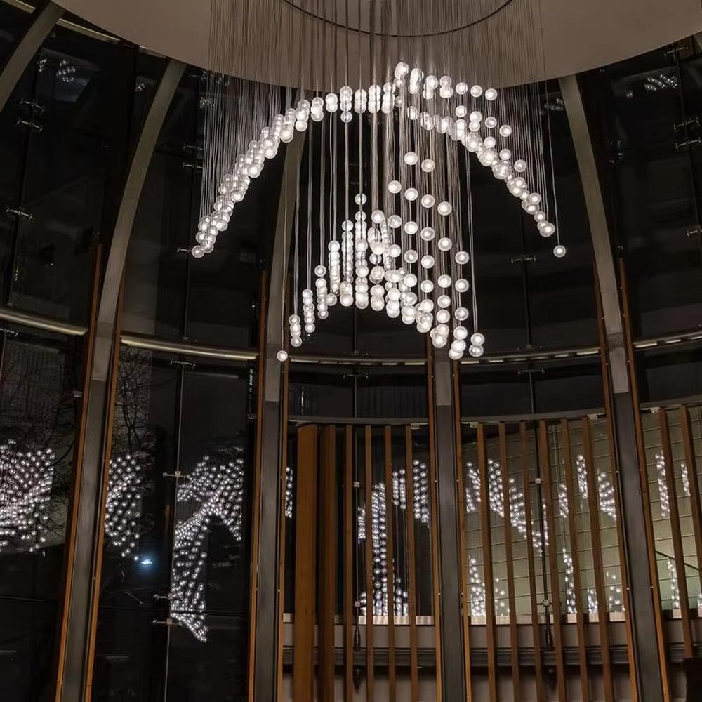 This is a modern artistic spherical light cluster chandelier with numerous white spherical lights arranged in a creative cluster via hanging wires. It features a highly immersive and artistic design with a futuristic ambiance. It is used for space lighting and decoration, creating a stunning visual focus and immersive light-shadow atmosphere. It is suitable for atriums of large commercial complexes, lobbies of high-end hotels, art galleries and exhibition halls and other places.