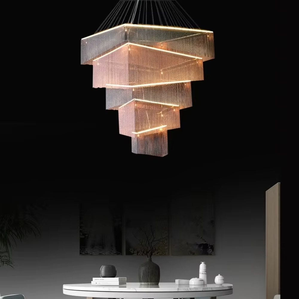 This is a modern artistic multi-layer square metal chain chandelier, composed of multi-layer square structures, paired with metal chains and LED light strips. It features soft and layered lighting, with a strong sense of modernity and spatial tension. It is used for space lighting and artistic decoration, creating a modern artistic and high-end atmosphere. Suitable for high-end hotel lobbies, art exhibition halls, high-ceiling spaces in luxury villas and other places.