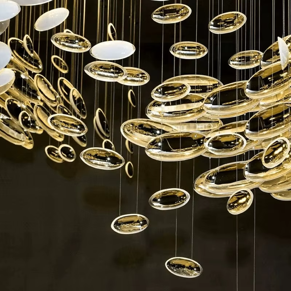 This is an artistic installation-style gold and white spiral glass piece chandelier, with numerous golden and white oval glass pieces hanging in a spiral and scattered manner, featuring strong artistic sense and visual impact, with brilliant light refraction. It is used for space lighting and artistic decoration, creating a luxurious artistic atmosphere. Suitable for high-end hotel lobbies, art exhibition halls, luxury shopping mall atriums and other places.