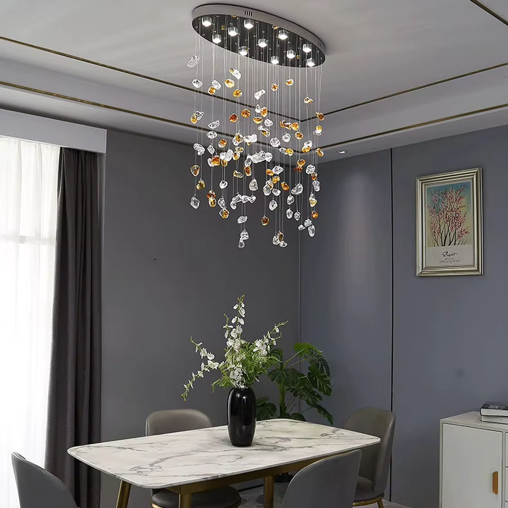 This is an artistic glass stone chandelier, with blue-green and transparent glass stones distributed irregularly in a hanging structure, featuring a modern artistic design with strong luxury artistic sense. It is used for space lighting and decoration, creating an artistic luxury atmosphere. It is suitable for modern luxury home living rooms, art exhibition halls, high-end restaurants and other places.
