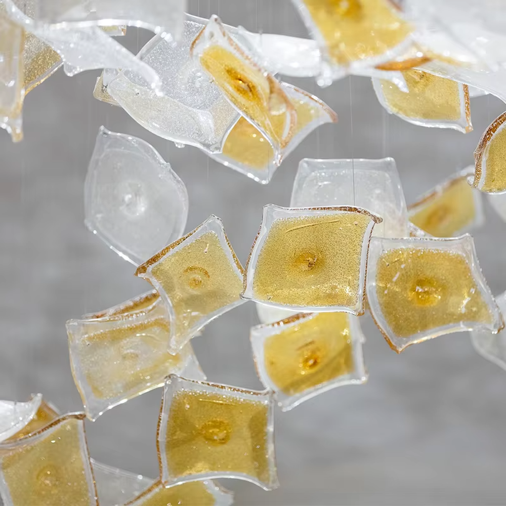 This is an artistic installation-style glass piece chandelier, with numerous transparent and golden glass pieces hanging in a scattered manner, featuring strong artistic sense, and the light reflects a brilliant visual effect. It is used for space lighting and artistic decoration, creating a luxurious artistic atmosphere. Suitable for high-end hotel lobbies, art exhibition halls, luxury shopping mall atriums and other places.