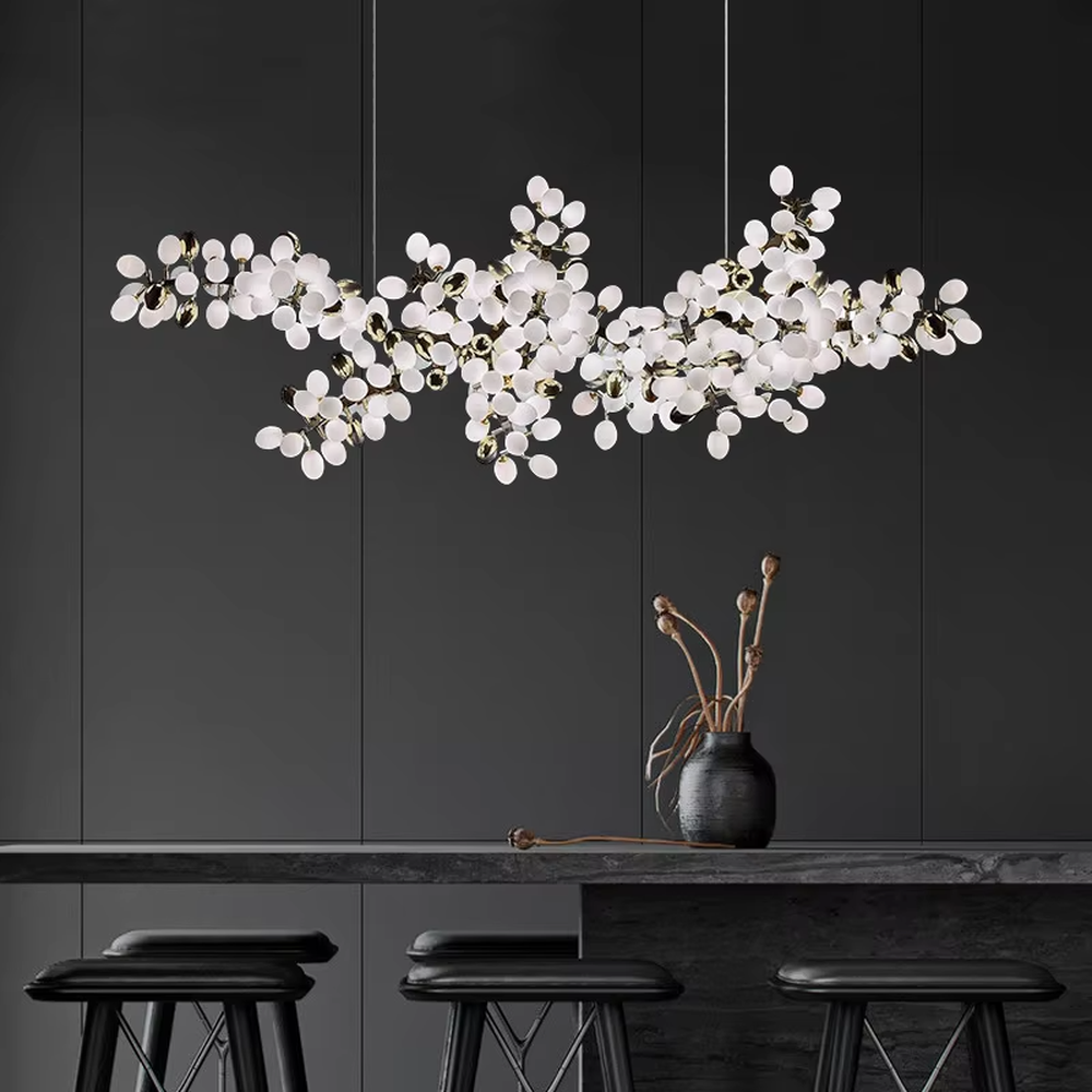 This is a light luxury artistic long strip flower branch-shaped chandelier, with golden metal branches paired with a large number of white spherical lampshades. The shape is like blooming flower branches, with soft and brilliant lighting, creating a light luxury artistic atmosphere.