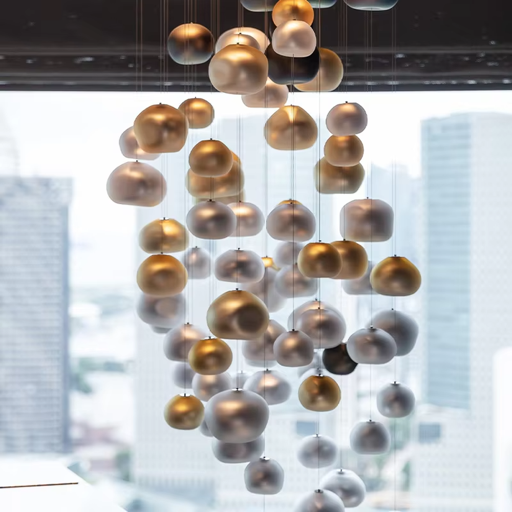 This artistic pendant chandelier consists of spherical lamp shades with a gradient from gold to silver, resembling flowing pearls or bubbles. It serves both lighting and decorative purposes, ideal for high-ceiling spaces, villa living rooms, art galleries, and high-end clubs.