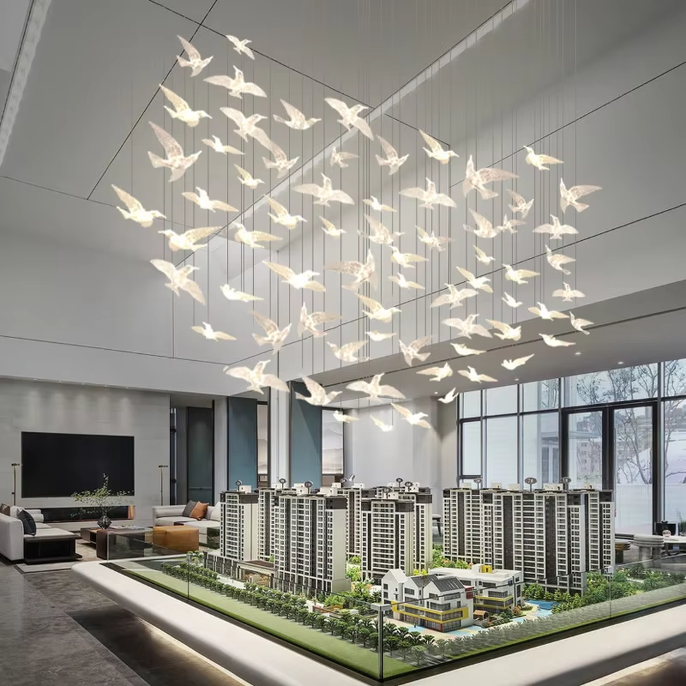 This art chandelier features bird shapes made of light-transmitting material, hung staggered with slender suspension rods, creating a vivid effect of a flock of birds flying, serving both lighting and decorative purposes, ideal for high-ceiling commercial spaces such as sales offices, hotel lobbies, and art exhibition halls.
