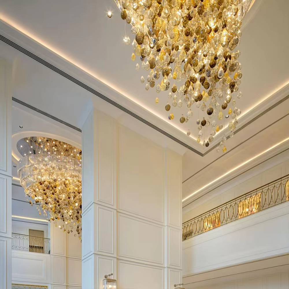 This large dome crystal chandelier features a multi-layered hanging teardrop design made of transparent and yellow-white gradient crystals, serving both lighting and artistic decoration purposes, with free design and professional engineering customization available, ideal for high-end high-ceiling spaces such as villa staircases, hotel lobbies, and sales offices.