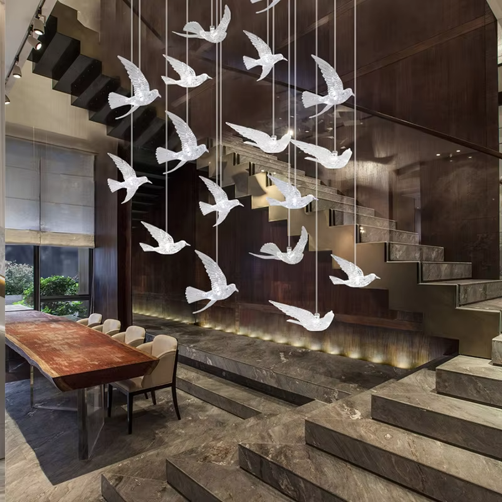 This art chandelier features bird shapes made of light-transmitting material, hung staggered with slender suspension rods, creating a vivid effect of a flock of birds flying, serving both lighting and decorative purposes, ideal for high-ceiling commercial spaces such as sales offices, hotel lobbies, and art exhibition halls.