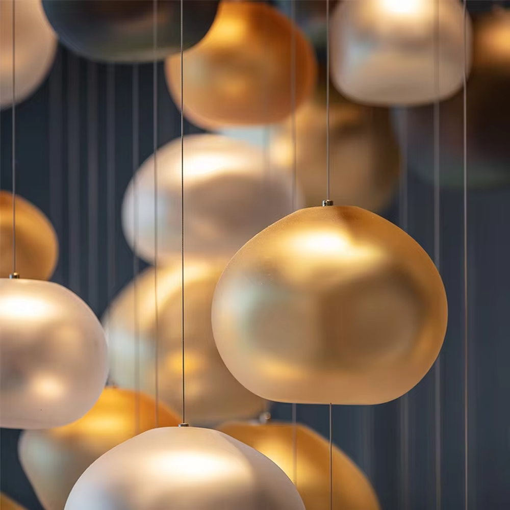 This artistic pendant chandelier consists of spherical lamp shades with a gradient from gold to silver, resembling flowing pearls or bubbles. It serves both lighting and decorative purposes, ideal for high-ceiling spaces, villa living rooms, art galleries, and high-end clubs.