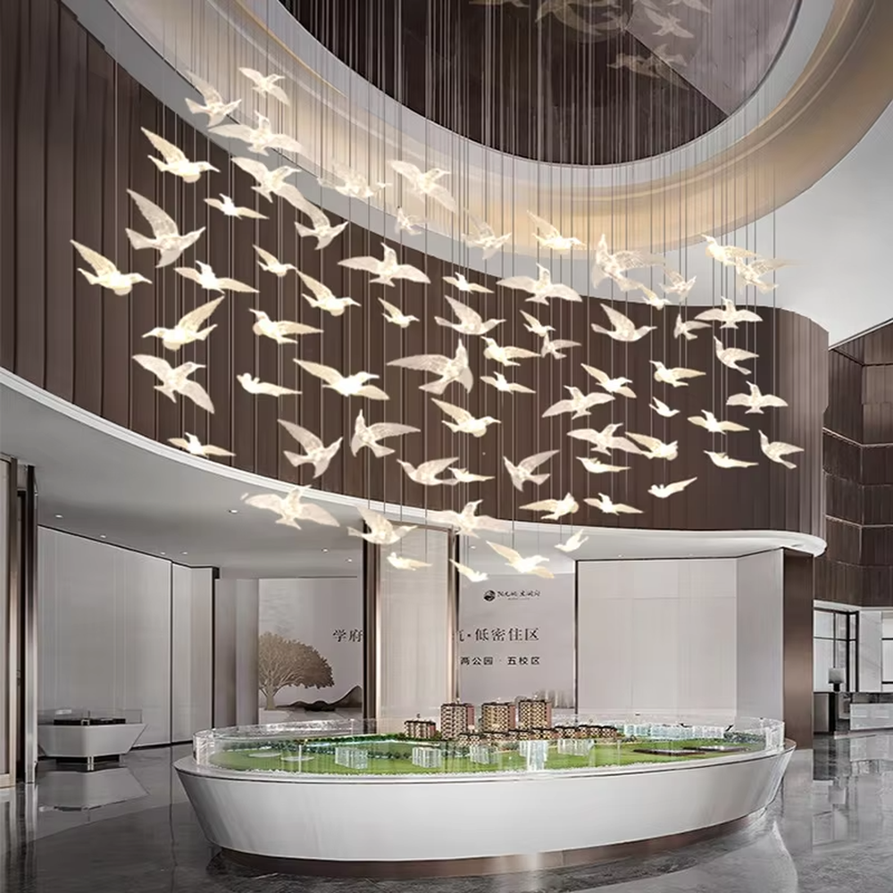 This art chandelier features bird shapes made of light-transmitting material, hung staggered with slender suspension rods, creating a vivid effect of a flock of birds flying, serving both lighting and decorative purposes, ideal for high-ceiling commercial spaces such as sales offices, hotel lobbies, and art exhibition halls.