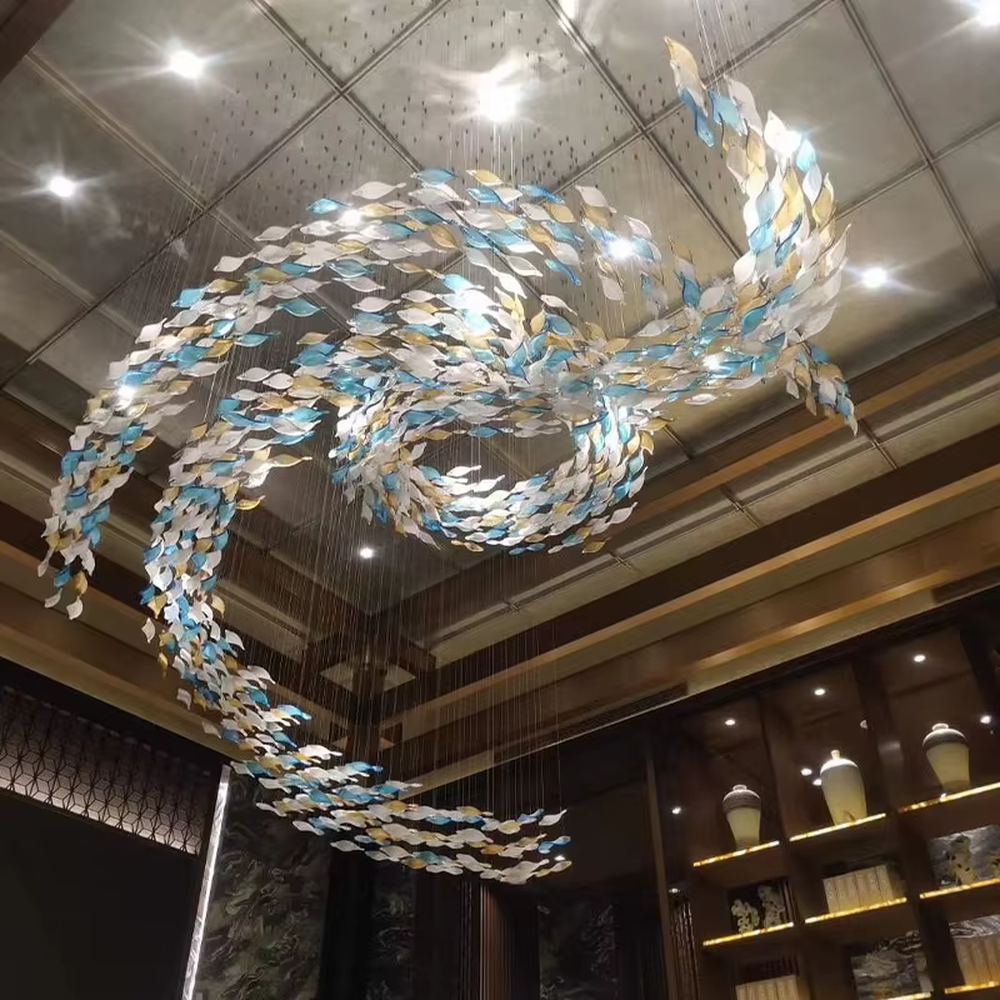 This large custom art glass chandelier features a streamlined school-of-fish/cloud-belt shape made of yellow-white gradient glass leaves, suspended in a floating manner, serving both lighting and artistic decoration purposes, ideal for high-ceiling commercial spaces such as sales offices, hotel lobbies, and high-end clubs.