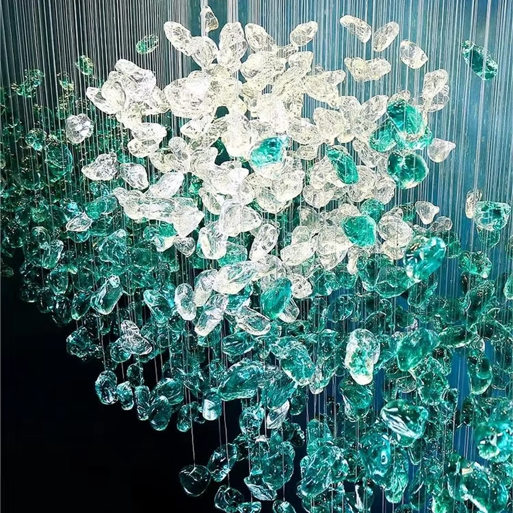 This large-scale art crystal chandelier features a long, flowing shape made of green-white gradient crystal pieces, like suspended green plants or ocean waves. It serves both lighting and artistic decorative purposes, ideal for high-ceiling commercial spaces such as hotel lobbies, sales offices, and high-end clubs.