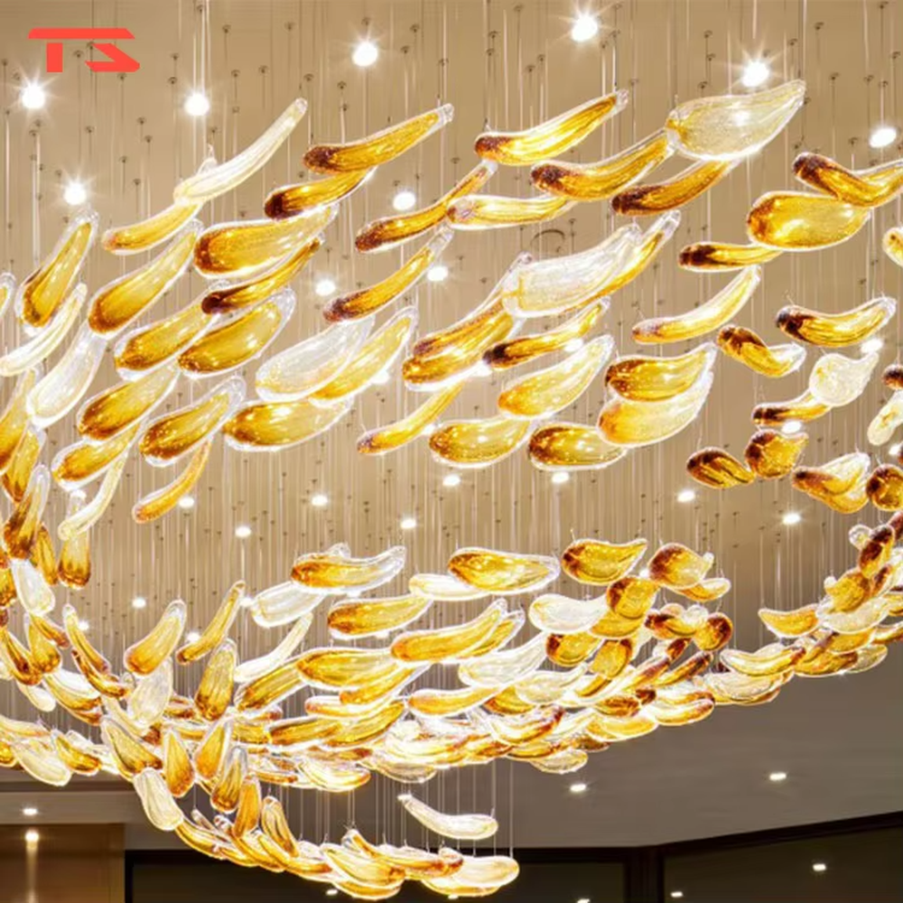This large custom art glass chandelier features a streamlined school-of-fish/cloud-belt shape made of yellow-white gradient glass leaves, suspended in a floating manner, serving both lighting and artistic decoration purposes, ideal for high-ceiling commercial spaces such as sales offices, hotel lobbies, and high-end clubs.