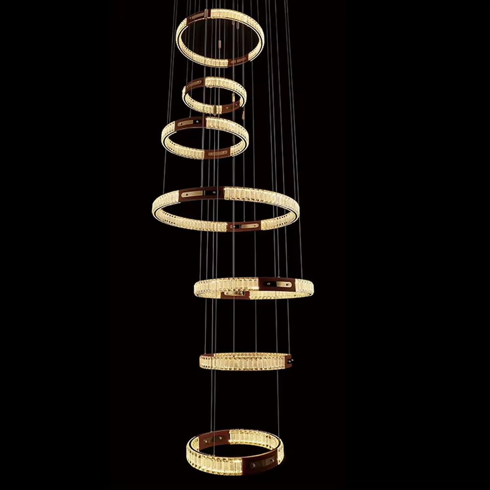 This is a light luxury style multi-layer staggered ring crystal chandelier, featuring a gold metal frame paired with transparent crystal strips. The layered ring shape resembles flowing light rhythm, emitting brilliant and luxurious light, serving both lighting and artistic decoration purposes, suitable for high-ceiling spaces such as villa high-ceiling living rooms, spiral staircases, hotel lobbies, and duplex voids.
