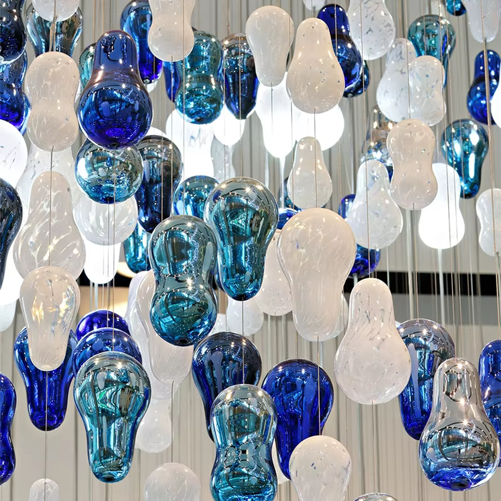 Art blue-white glass bead spiral chandelier (gradient color beads + curved shape), warm light effect, creating a dynamic artistic atmosphere for high-end public spaces.