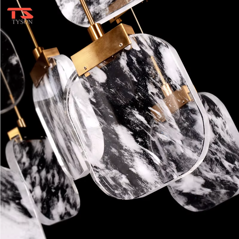 This is a light luxury style duplex crystal chandelier, featuring a gold circular base paired with staggered and hanging marble-patterned crystal blocks. Light refracts through the crystals to create brilliant and luxurious lighting effects, serving both lighting and artistic decoration purposes, suitable for high-ceiling spaces such as villa high-ceiling living rooms, duplex voids, hotel lobbies, and spiral staircases.