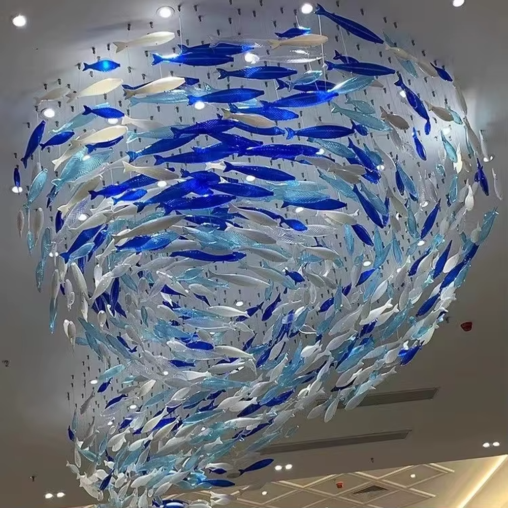 Art fish school-shaped chandelier (blue-white gradient glass fish + warm light), warm light effect, creating a dynamic and natural atmosphere for high-end public spaces.