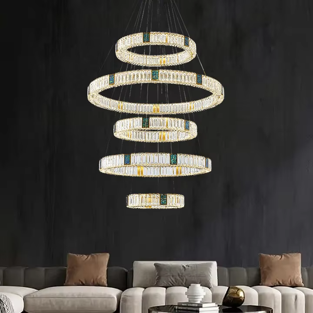 This is a light luxury artistic spiral crystal chandelier, featuring multi-layered circular crystal strips paired with a gold metal frame and emerald accents, shaped like a flowing tornado. Light refracts through the crystals to create brilliant and luxurious lighting effects, serving both lighting and artistic decoration purposes, suitable for high-ceiling spaces such as villa high-ceiling living rooms, duplex voids, hotel lobbies, and high-end clubs.