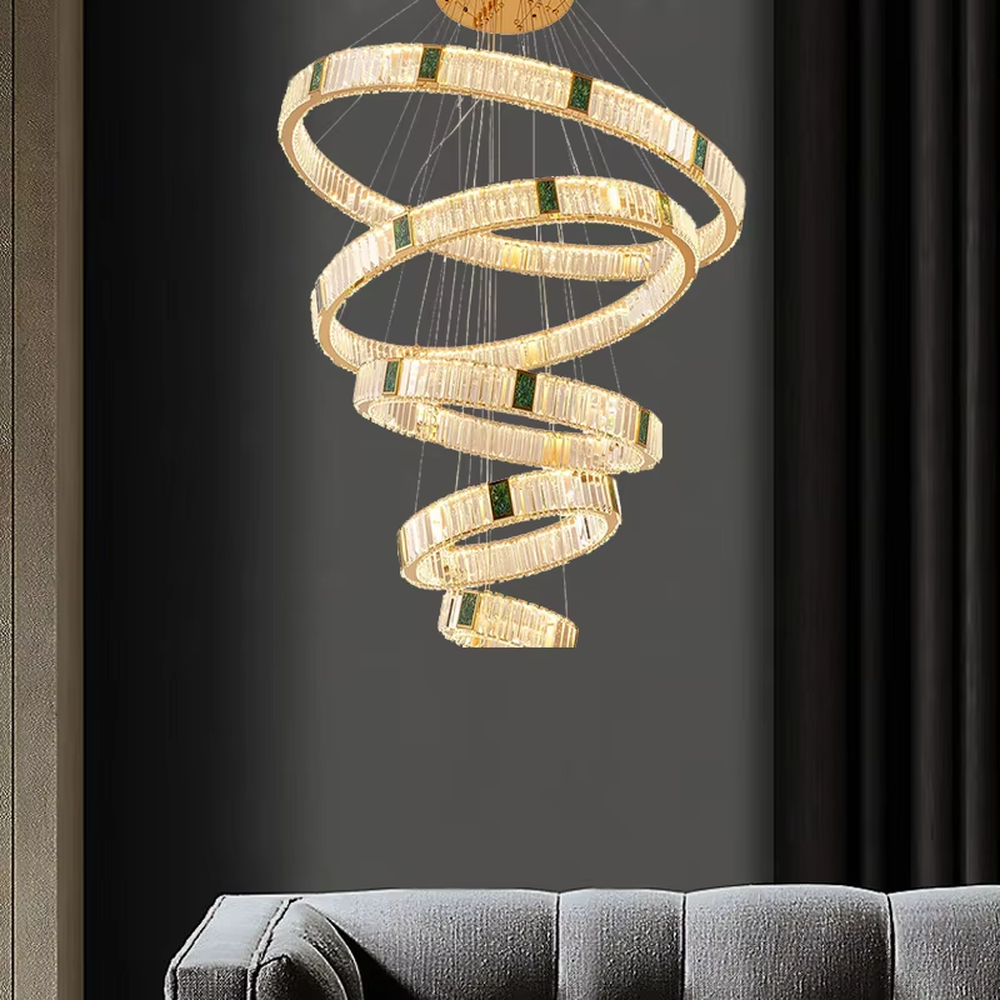 This is a light luxury artistic spiral crystal chandelier, featuring multi-layered circular crystal strips paired with a gold metal frame and emerald accents, shaped like a flowing tornado. Light refracts through the crystals to create brilliant and luxurious lighting effects, serving both lighting and artistic decoration purposes, suitable for high-ceiling spaces such as villa high-ceiling living rooms, duplex voids, hotel lobbies, and high-end clubs.