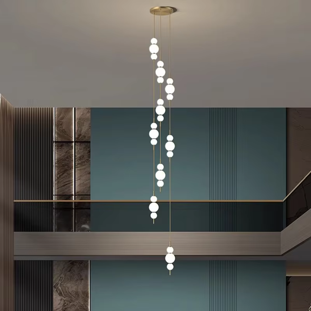Nordic light luxury style staggered spherical chandelier, with gold metal suspension rods paired with milky white luminous bulbs, arranged in a cascading staggered layout. It emits soft and warm light, combining decorativeness and lighting function, suitable for core lighting and atmosphere creation in high-ceiling spaces such as duplex stairs, high-ceiling living rooms, and villa hollow areas.
