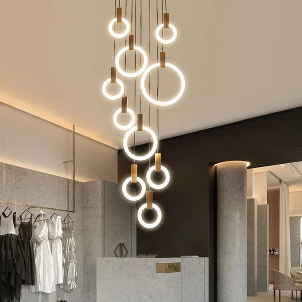 Modern light luxury multi-layer ring LED chandelier, composed of luminous rings of varying sizes and gold metal top bases, hanging in a staggered manner to present a flowing rhythmic sense. It emits soft and even light, combining decorativeness and lighting function, suitable for main lighting and atmosphere creation in high-ceiling spaces such as duplex stairs, high-ceiling living rooms, and villas.