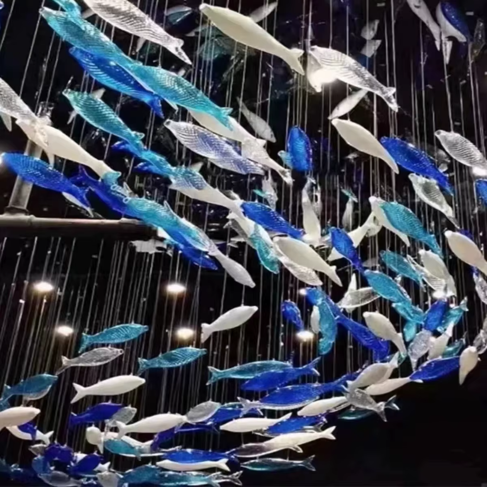 Art fish school-shaped chandelier (blue-white gradient glass fish + warm light), warm light effect, creating a dynamic and natural atmosphere for high-end public spaces.
