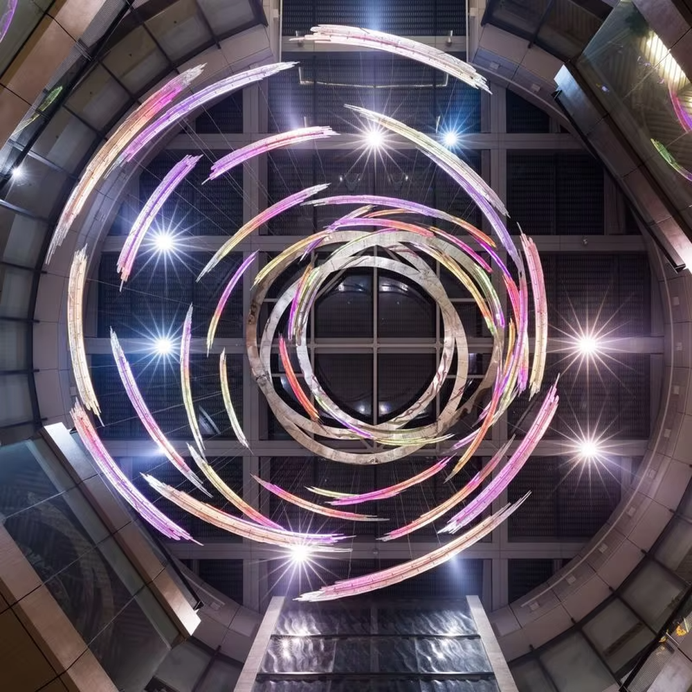 Art gradient spiral LED chandelier (color light stripes + ring structure), colorful warm light effect, creating a futuristic artistic atmosphere for high-end space decoration.