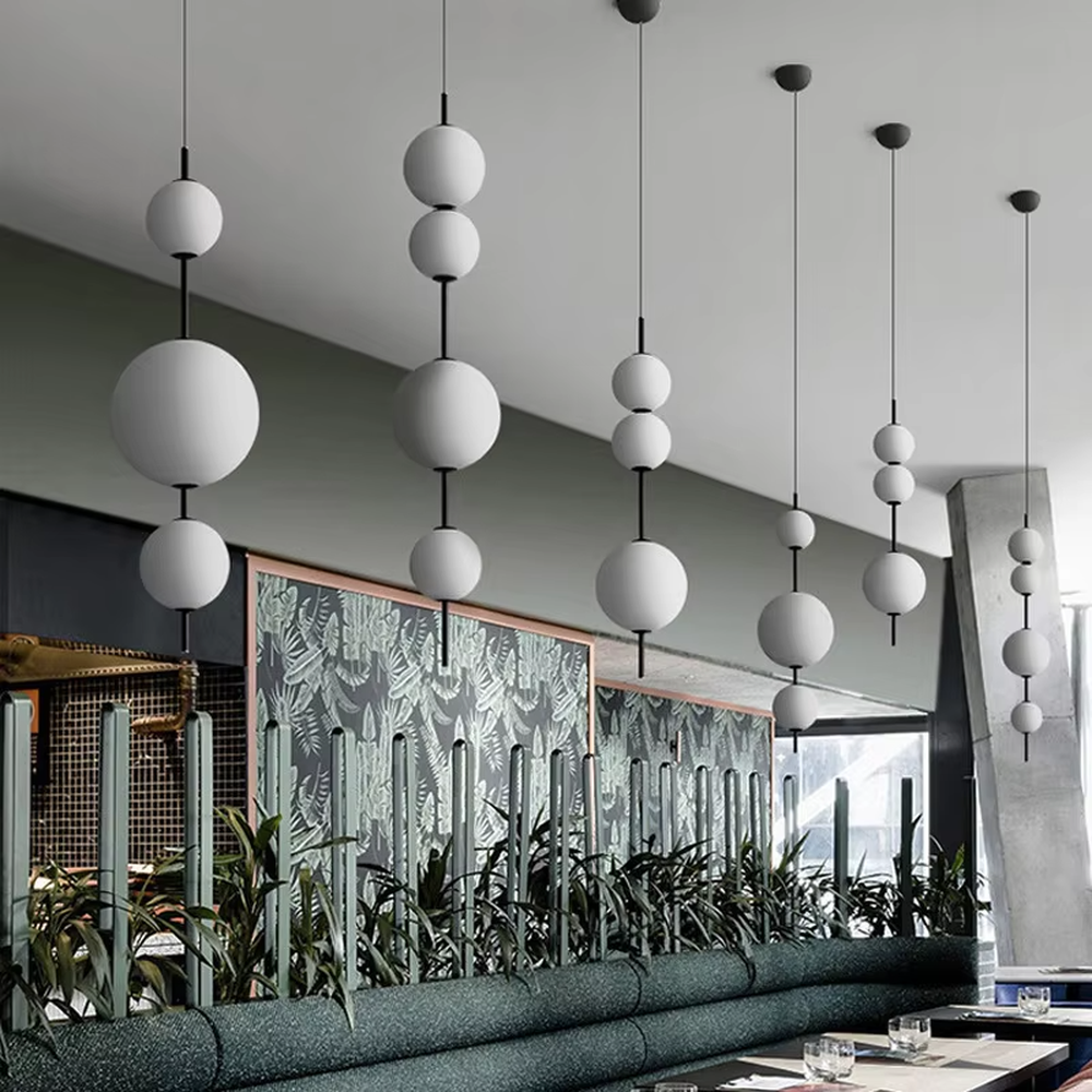 Modern tiered glass ball chandelier (black-white tiered balls + minimalist hanging rod), warm light effect, creating a simple and artistic space atmosphere.