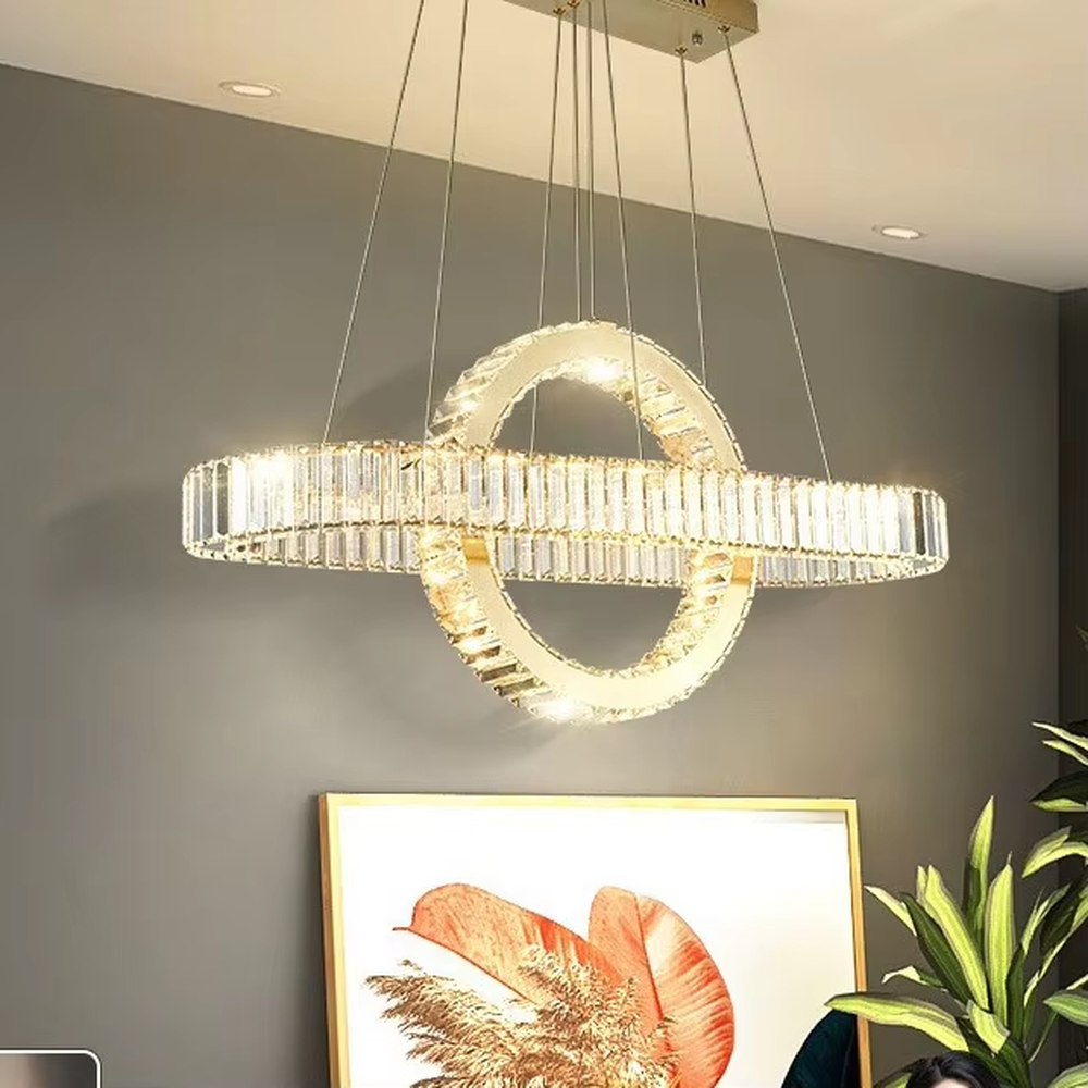 This is a light luxury and luxurious long strip ring crystal chandelier, with a golden metal frame paired with transparent crystals, adopting a combination of long strip and ring shape. When lit, the light is brilliant and gorgeous, creating a high-end light luxury atmosphere.