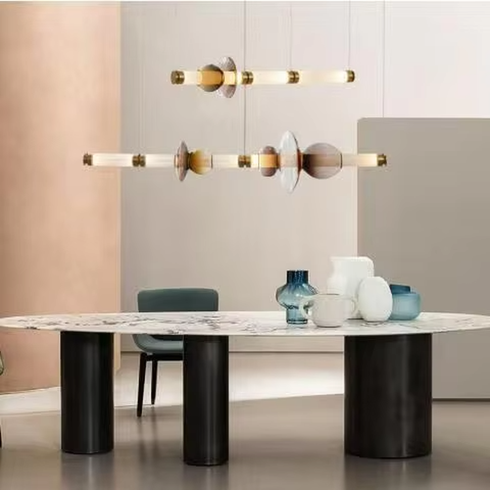 This is a modern artistic layered colorful glass chandelier, featuring a spliced shape of transparent, amber and blue glass, paired with golden metal connectors. The lighting is soft and colorful, creating an artistic and high-end atmosphere.