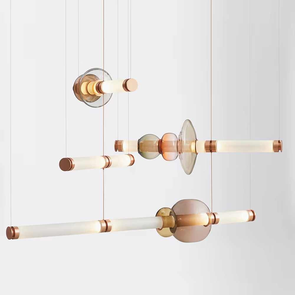 Modern artistic hanging combination chandelier, gradient glass components + copper metal decorations + milky white long tubes, soft lighting, creating an artistic minimalist atmosphere.