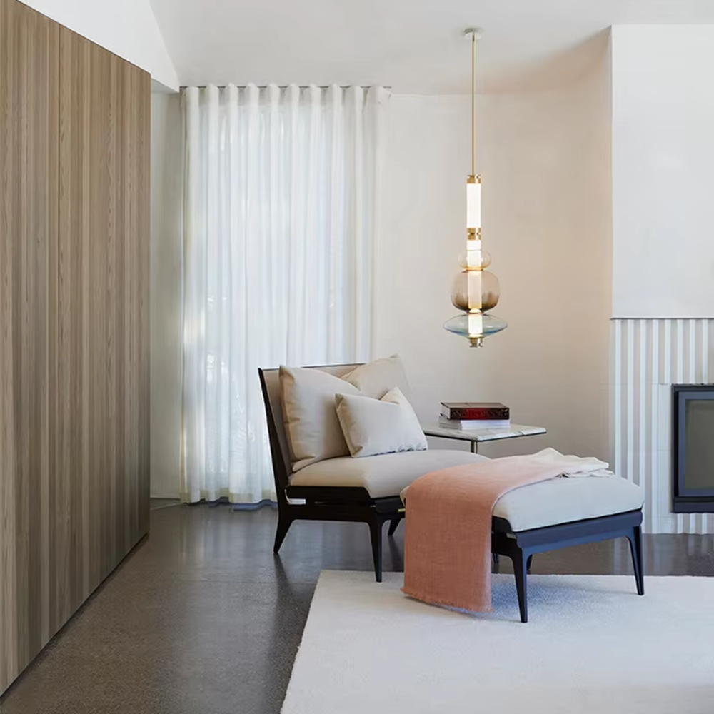 This is a modern artistic layered colorful glass chandelier, featuring a spliced shape of transparent, amber and blue glass, paired with golden metal connectors. The lighting is soft and colorful, creating an artistic and high-end atmosphere.