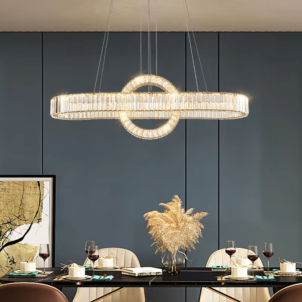 This is a light luxury and luxurious long strip ring crystal chandelier, with a golden metal frame paired with transparent crystals, adopting a combination of long strip and ring shape. When lit, the light is brilliant and gorgeous, creating a high-end light luxury atmosphere.