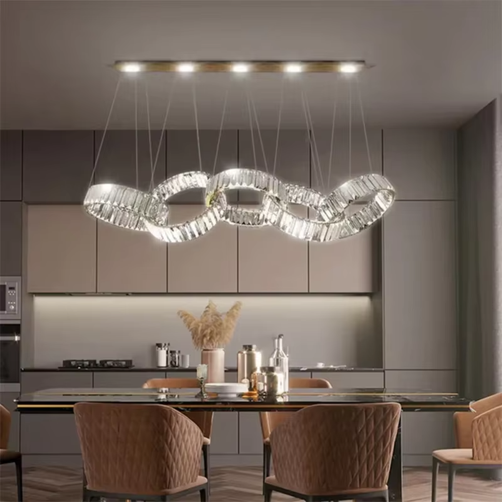 This is a modern light luxury style interlocking crystal chandelier, composed of transparent cut crystal strips forming a chain-like structure, paired with a gold metal suspension base. Light refracts through the crystals to create brilliant and dynamic lighting effects, serving both lighting and artistic decoration purposes, suitable for quality-focused scenarios such as large flat-floor dining rooms, villa living rooms, high-end clubs, and showrooms.