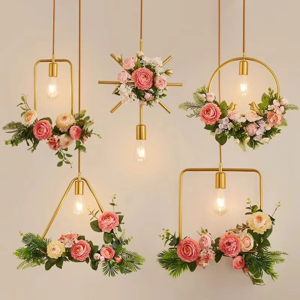 This is a romantic fresh-style geometric frame floral combination small chandelier, including golden metal star/triangle/circle frames, paired with pink-white artificial flowers and green plant decorations, and retro bulbs. The lighting is warm and soft, creating a romantic fresh atmosphere.