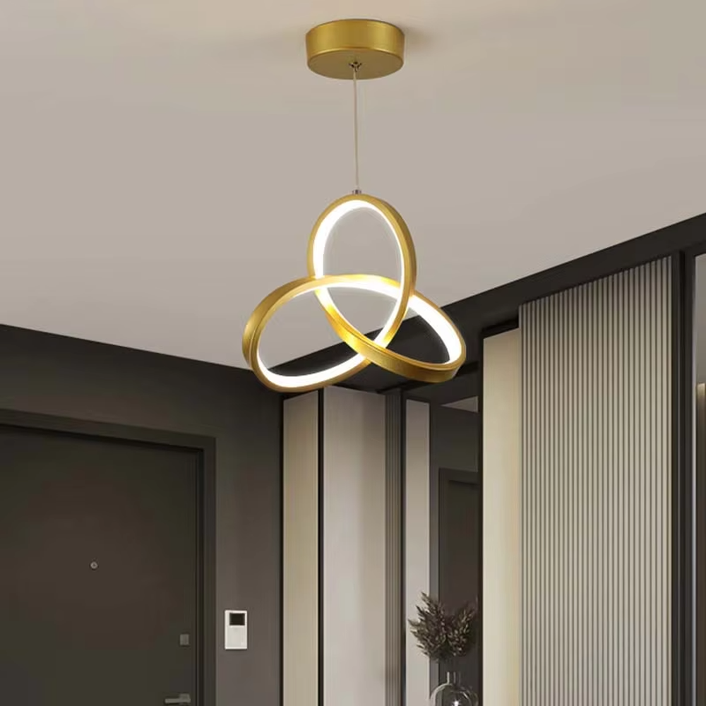 Modern minimalist black-gold interwoven triple-ring LED pendant light, warm light effect, creating a minimalist artistic space atmosphere.