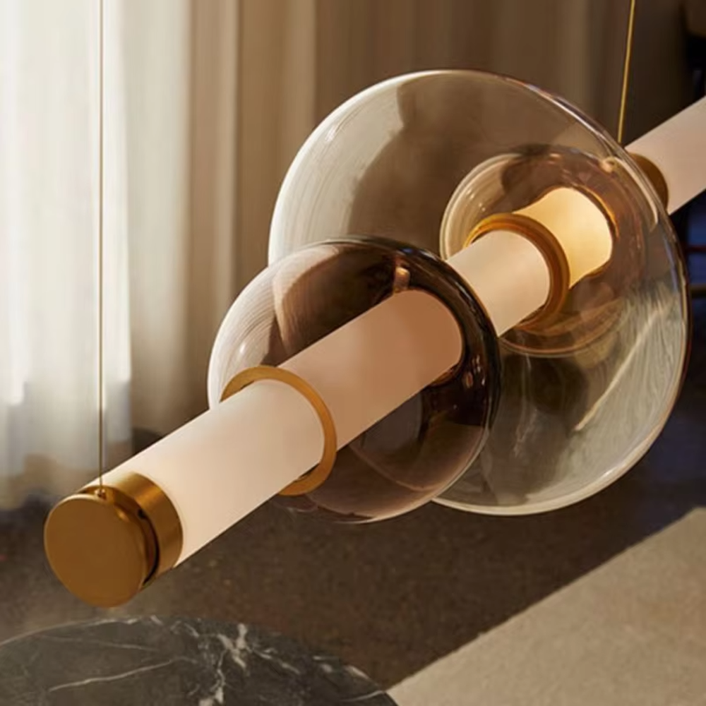 This is a modern artistic layered colorful glass chandelier, featuring a spliced shape of transparent, amber and blue glass, paired with golden metal connectors. The lighting is soft and colorful, creating an artistic and high-end atmosphere.