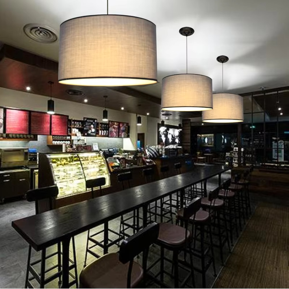 Minimalist beige fabric cylindrical hanging chandelier, metal suspension rod + fabric lampshade, soft and uniform lighting, creating a warm and leisure atmosphere.