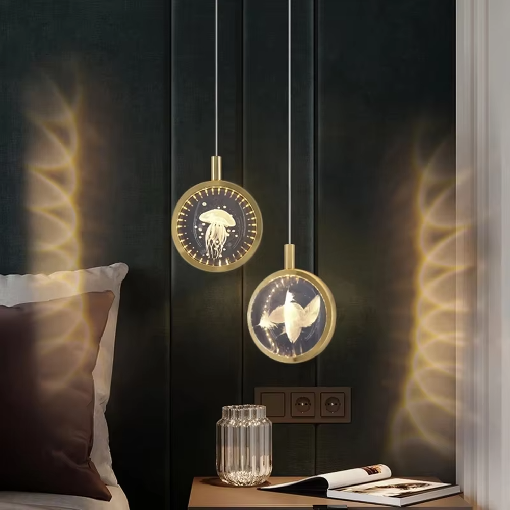 This light luxury small round chandelier features a gold metal frame, a transparent panel with delicate patterns such as jellyfish/birds, and projects ripple light and shadow on the wall when lit, serving both lighting and decorative purposes, ideal for bedroom bedside tables, light luxury homestays, high-end hotel rooms and other spaces.