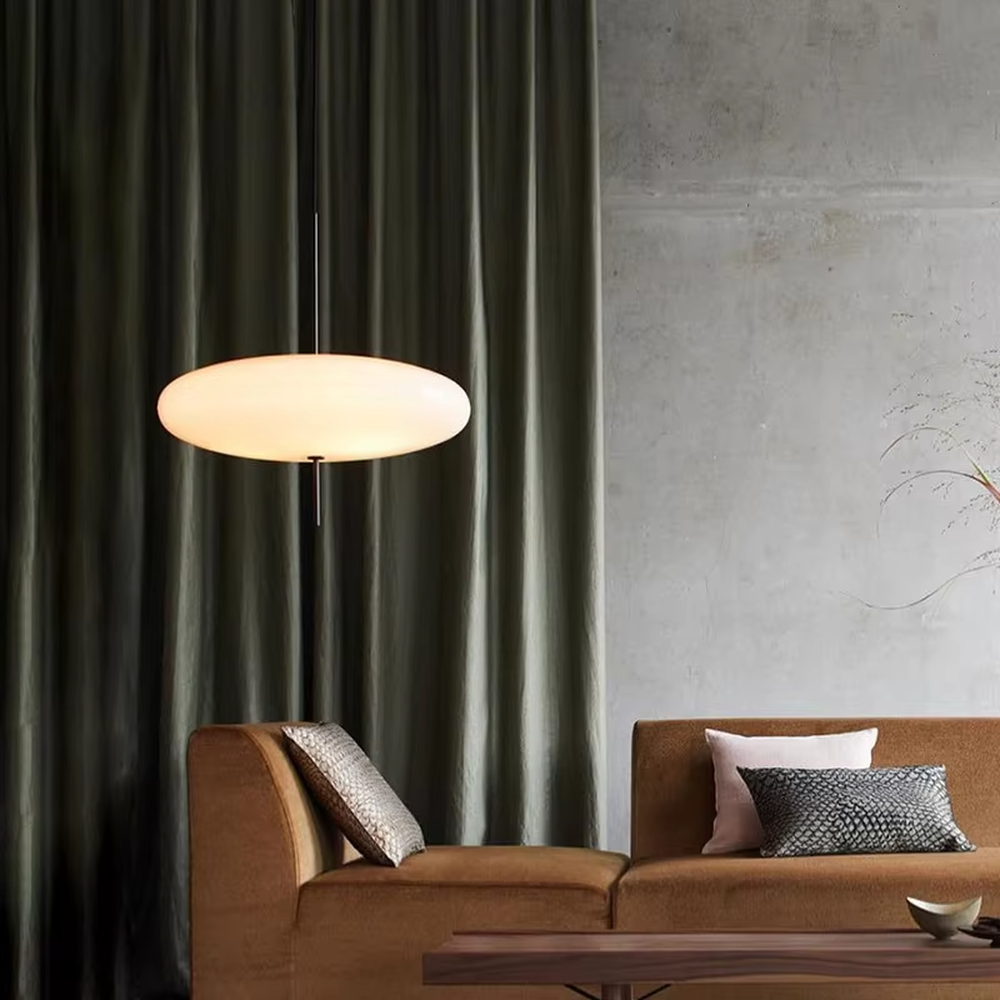 This modern minimalist flat round chandelier features a milky white frosted acrylic lampshade, paired with a thin black suspension rod, transmitting light softly. It serves both lighting and decorative purposes, ideal for modern minimalist spaces such as living rooms, bedrooms, and light luxury restaurants.