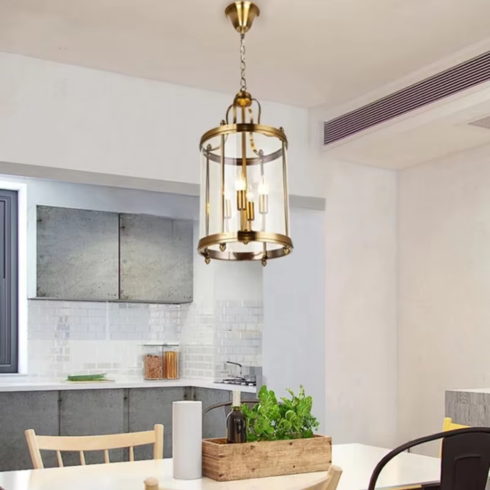 Light luxury golden metal cage-style cylindrical glass cover candelabra chandelier, golden frame + transparent cylindrical glass cover + candle-shaped bulbs, soft warm light, suitable for modern minimalist dining area atmosphere.