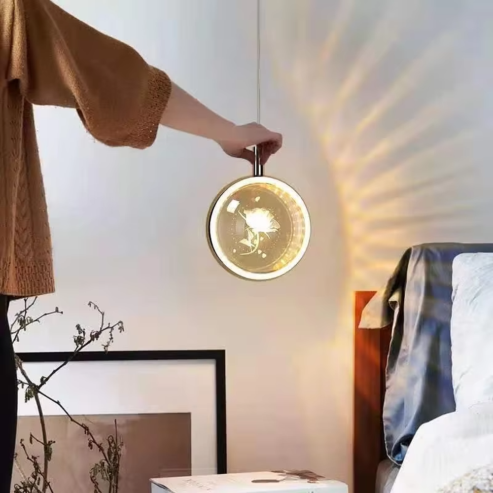 This light luxury small round chandelier features a gold metal frame, a transparent panel with delicate patterns such as jellyfish/birds, and projects ripple light and shadow on the wall when lit, serving both lighting and decorative purposes, ideal for bedroom bedside tables, light luxury homestays, high-end hotel rooms and other spaces.