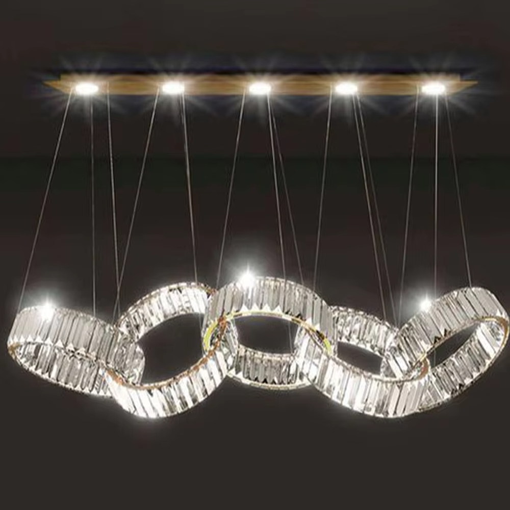 This is a modern light luxury style interlocking crystal chandelier, composed of transparent cut crystal strips forming a chain-like structure, paired with a gold metal suspension base. Light refracts through the crystals to create brilliant and dynamic lighting effects, serving both lighting and artistic decoration purposes, suitable for quality-focused scenarios such as large flat-floor dining rooms, villa living rooms, high-end clubs, and showrooms.