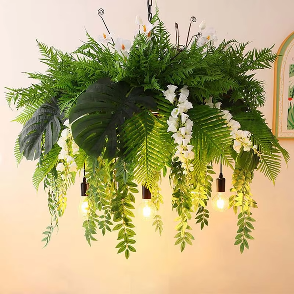 This is a natural and romantic floral retro chandelier, decorated with a large number of artificial flowers (pink and purple roses, etc.) and green plants (ferns, monstera leaves), paired with retro bulbs and a black metal frame. The design is natural and warm, with soft warm yellow lighting. It is used for space lighting and decoration, creating a natural romantic and warm retro atmosphere. Suitable for wedding venues, literary cafes, Nordic-style homestays, nature-themed restaurants and other places.